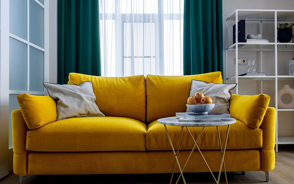 Желтый диван в интерьере комнаты, бирюзовые шторы 